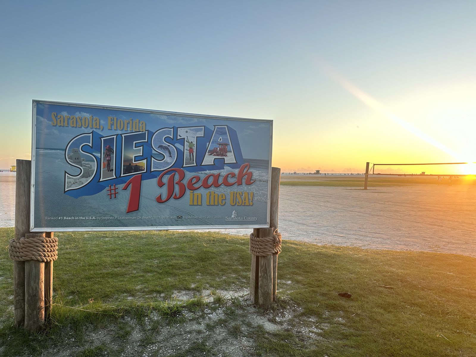 Sarasota County sign at Siesta Public Beach at sunset, noting the beach was ranked number one in the USA by Dr. Beach and TripAdvisor