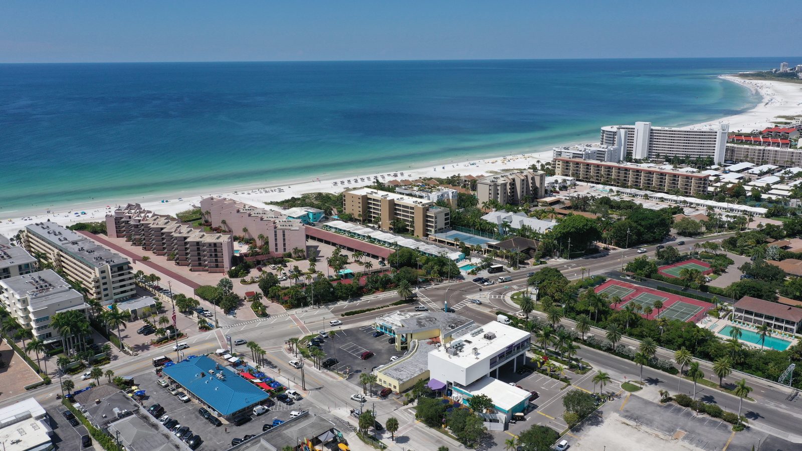 Low-rise resorts and shops set back from Crescent Beach on Siesta Key, with the Gulf of Mexico beyond