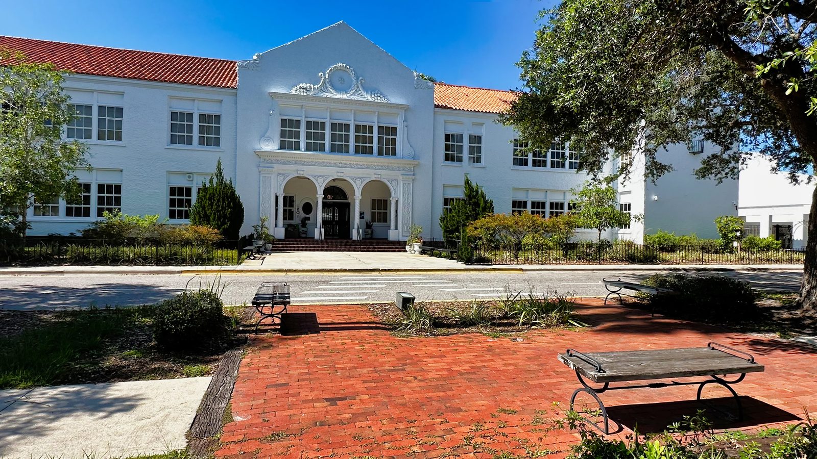 The 1926 Mediterranean Revival facade of the historic Southside School behind brick walkways and park benches